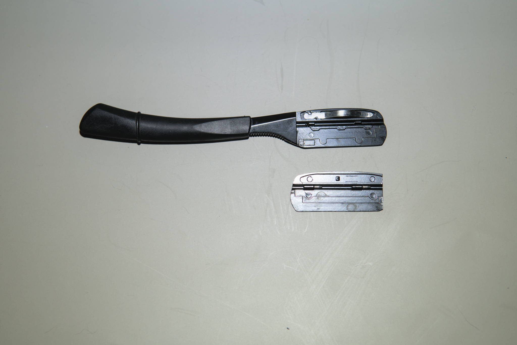 A swappable blade, fixed handle straight razor with the blade compartment open & parts shown