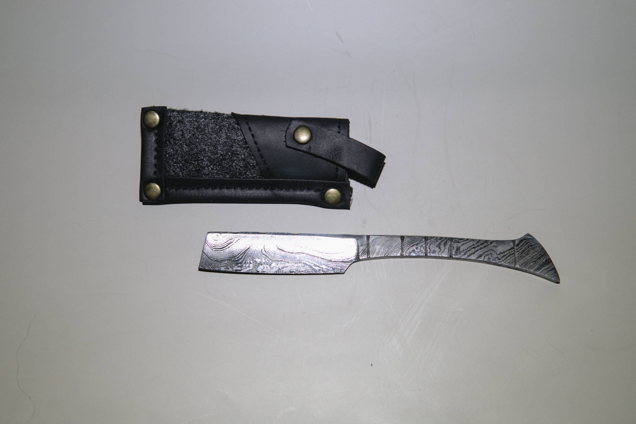 A damascus straight razor next to its case