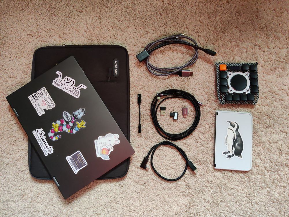 A soft case, Nexdock, usb wires, PuckBuddy and Surface Duo neatly arranged on carpet